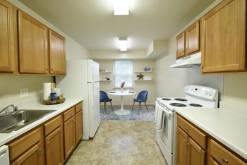 Kitchen with white appliances and wooden cabinets at Woodridge Apartments, Randallstown, MD